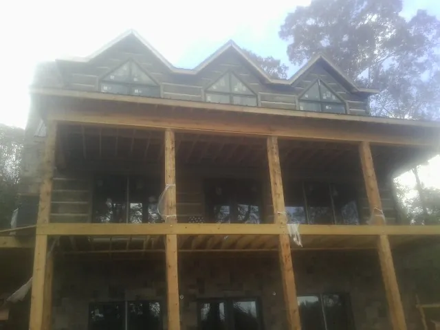 Dormers and porch framing on a large log home under construction — Roof Coating work by our crew in Keokuk