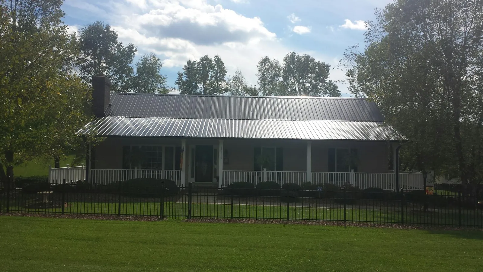 Gray metal roof on a brick ranch with a full width front porch — Gutter Guard Installation work by our crew in Keokuk