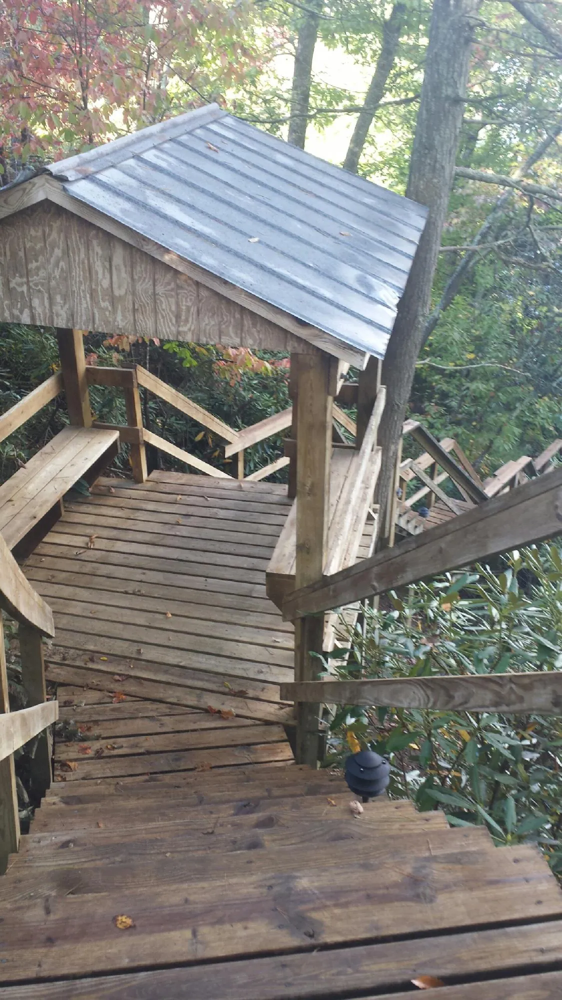 Metal roofed shelter over wooden steps on a wooded walkway — Skylight Repair & Installation work by our crew in Keokuk