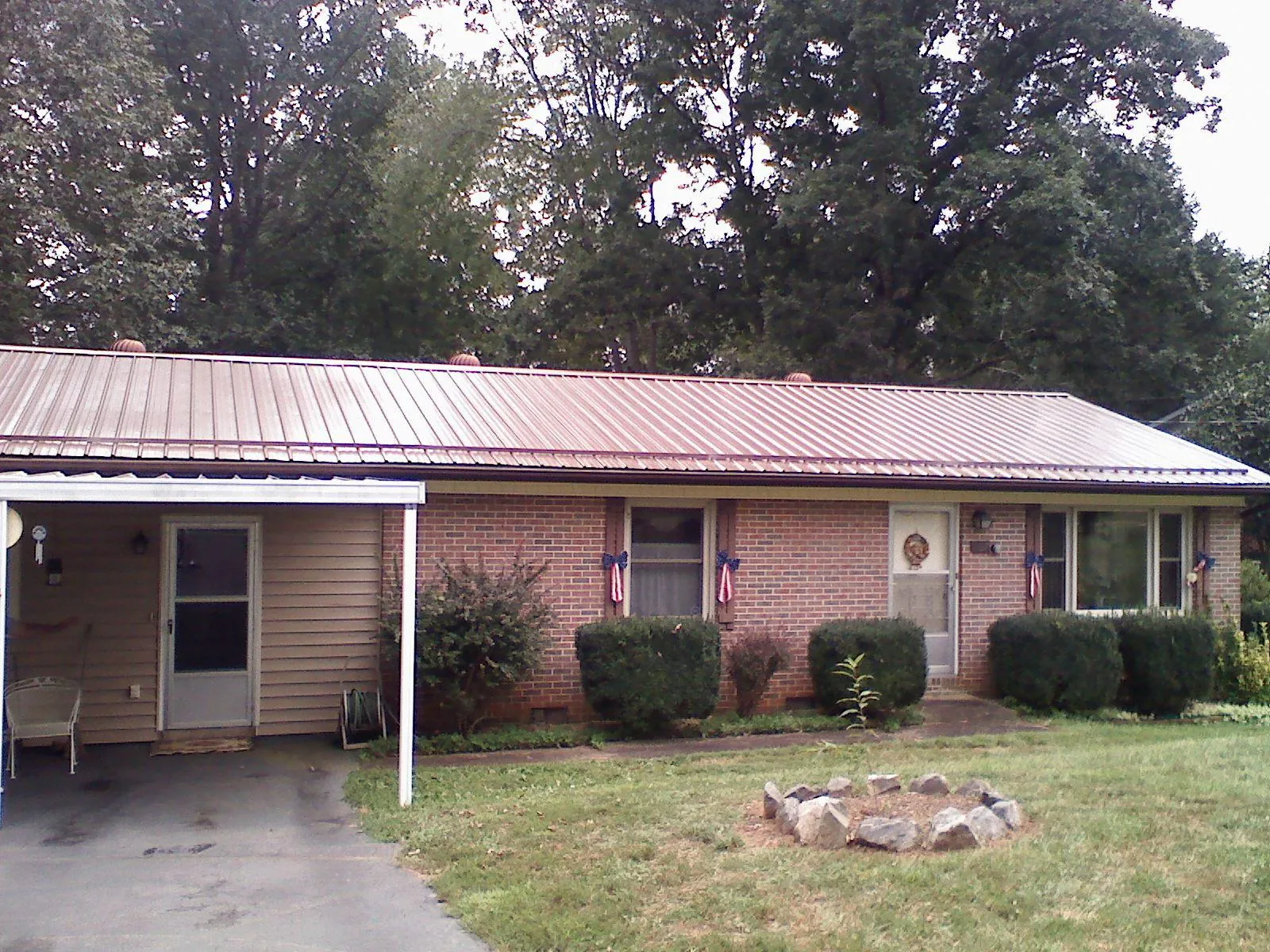 Bronze metal roof and carport on a brick ranch home — Roof Repair work by our crew in Keokuk