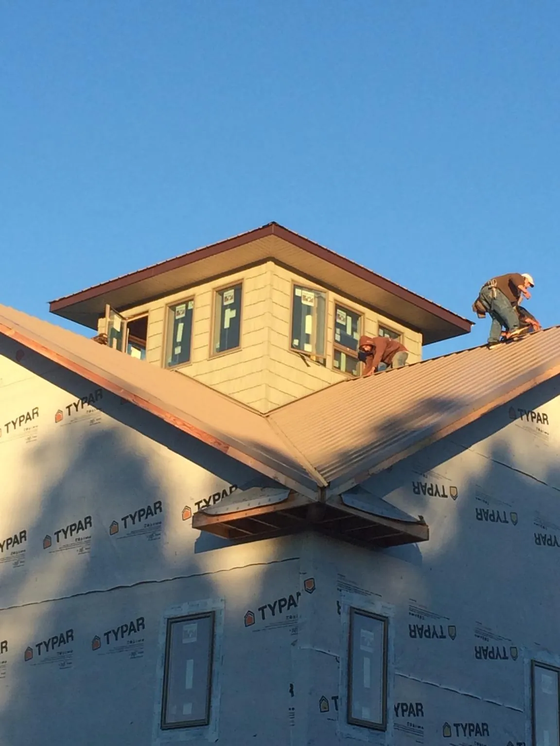 Roofers working around a rooftop cupola on a new metal roof at sunset — Roof Waterproofing in Keokuk by Roofing Brothers